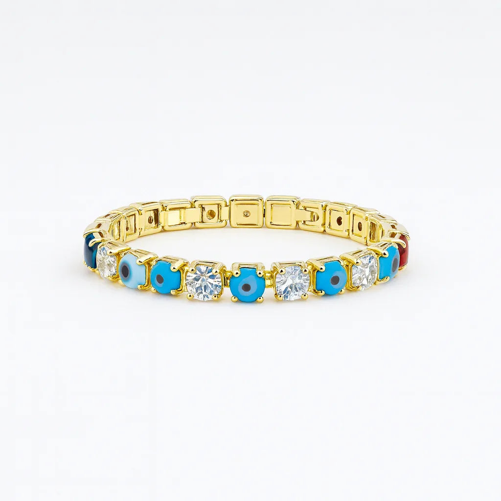 Gold tennis bracelet with alternating blue evil eye charms and clear gemstones on white background
