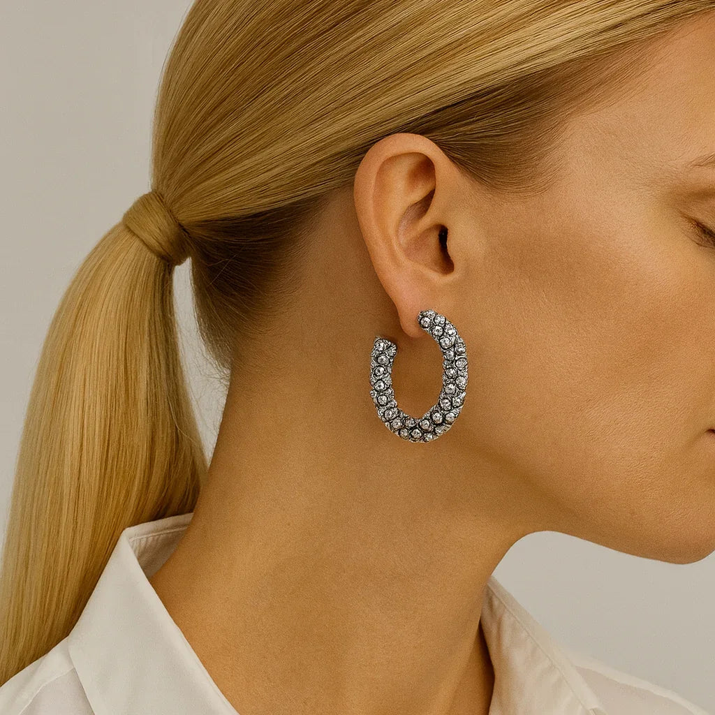 Woman wearing large crystal hoop earrings, close-up of ear and jewelry, minimalist background
