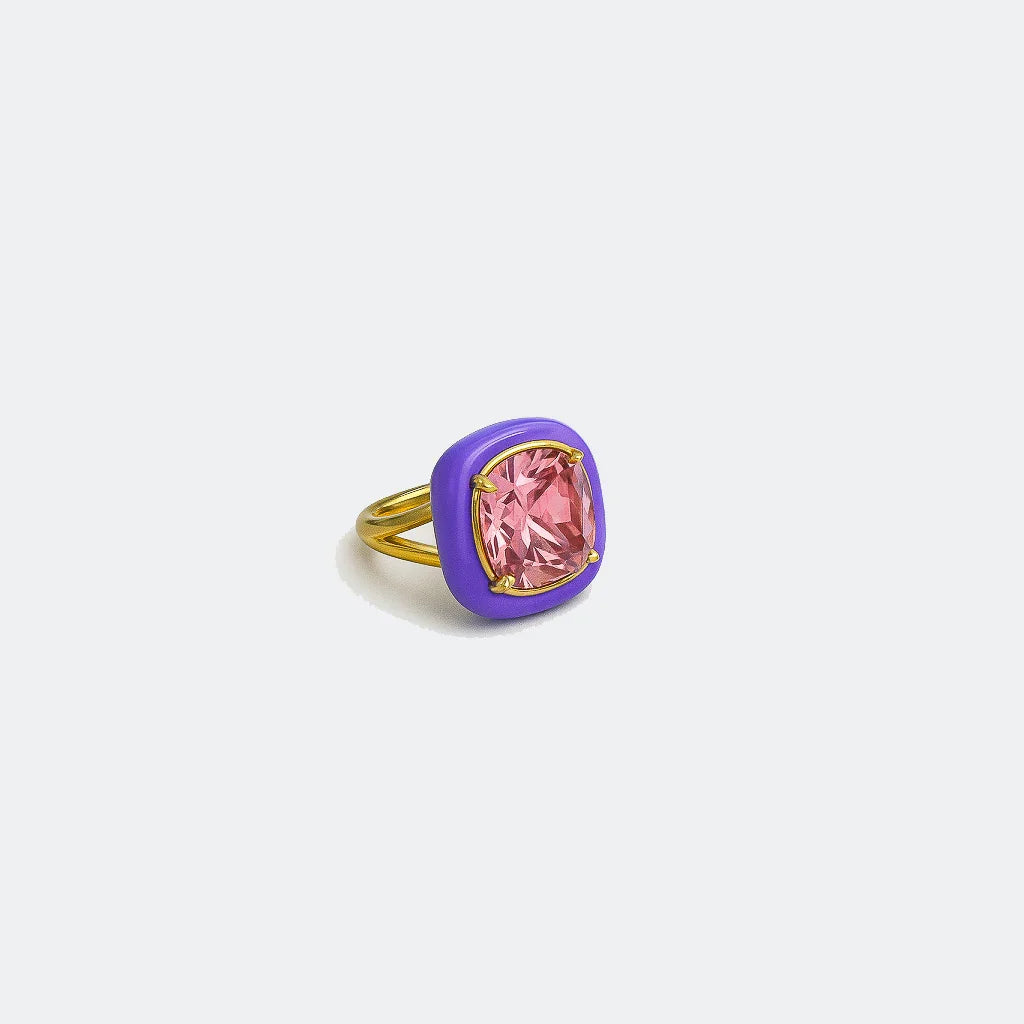 Gold ring with a large pink gemstone and purple enamel setting on white background.