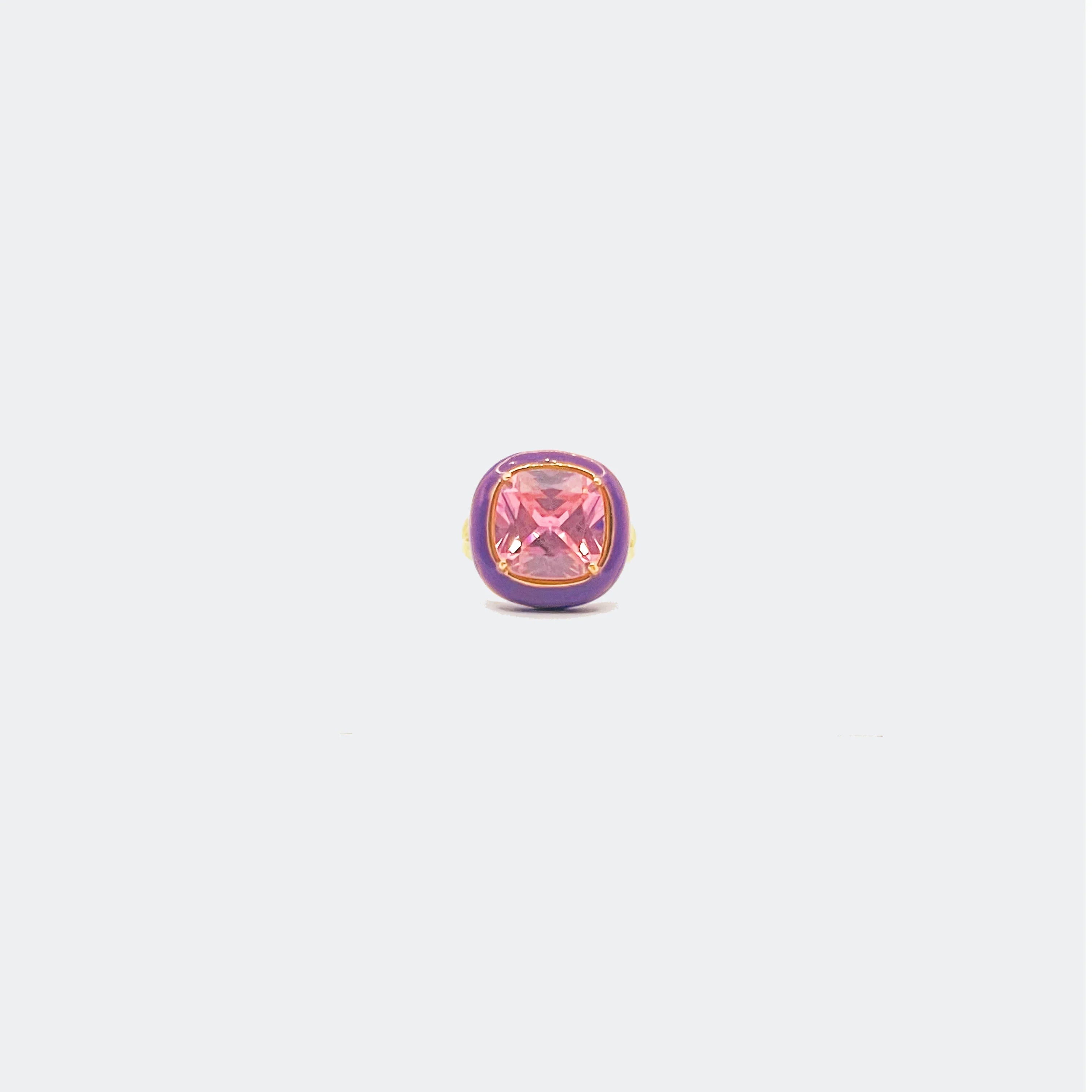 Purple and gold ring featuring a square pink gemstone on a light background