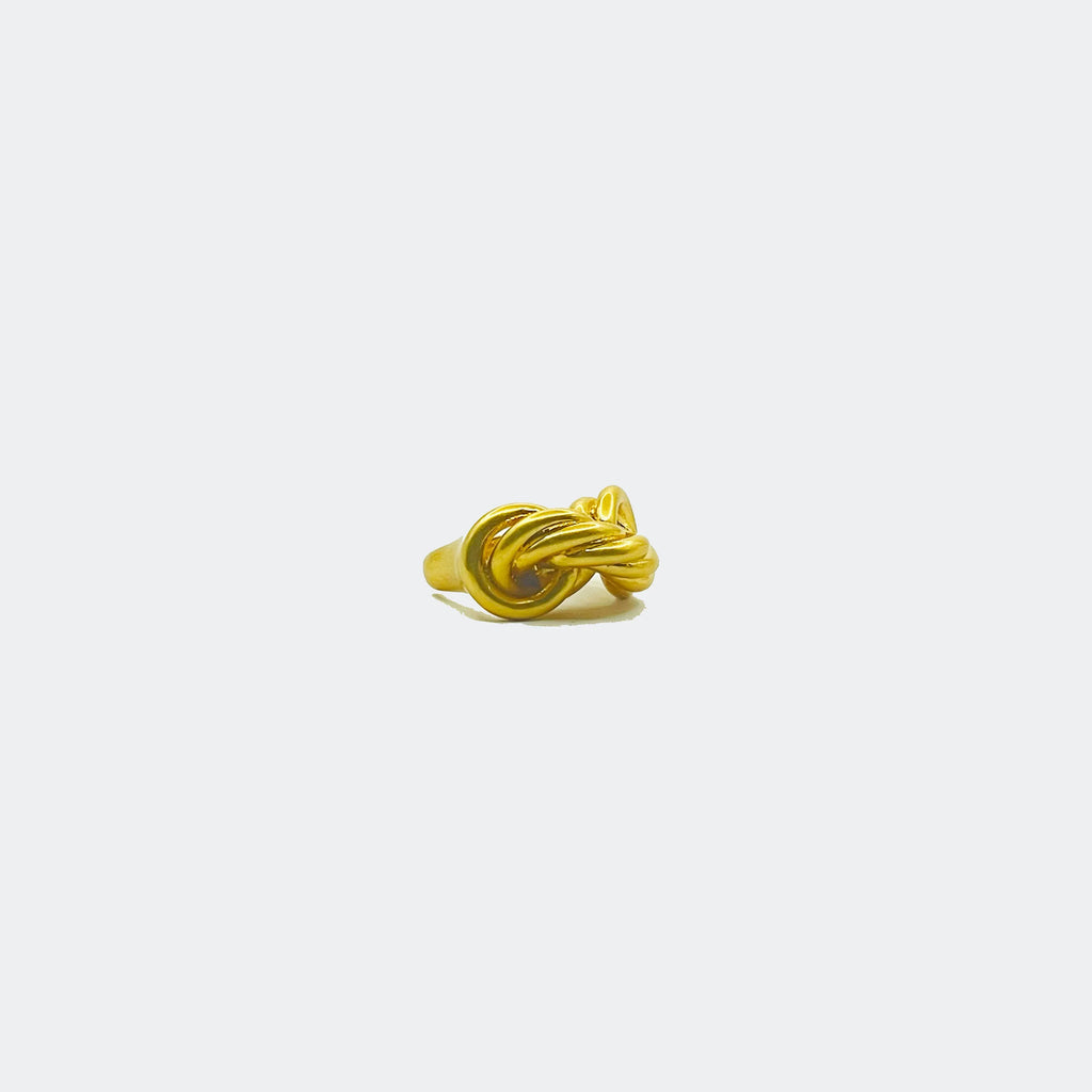 Gold knot ring with twisted design on plain white background