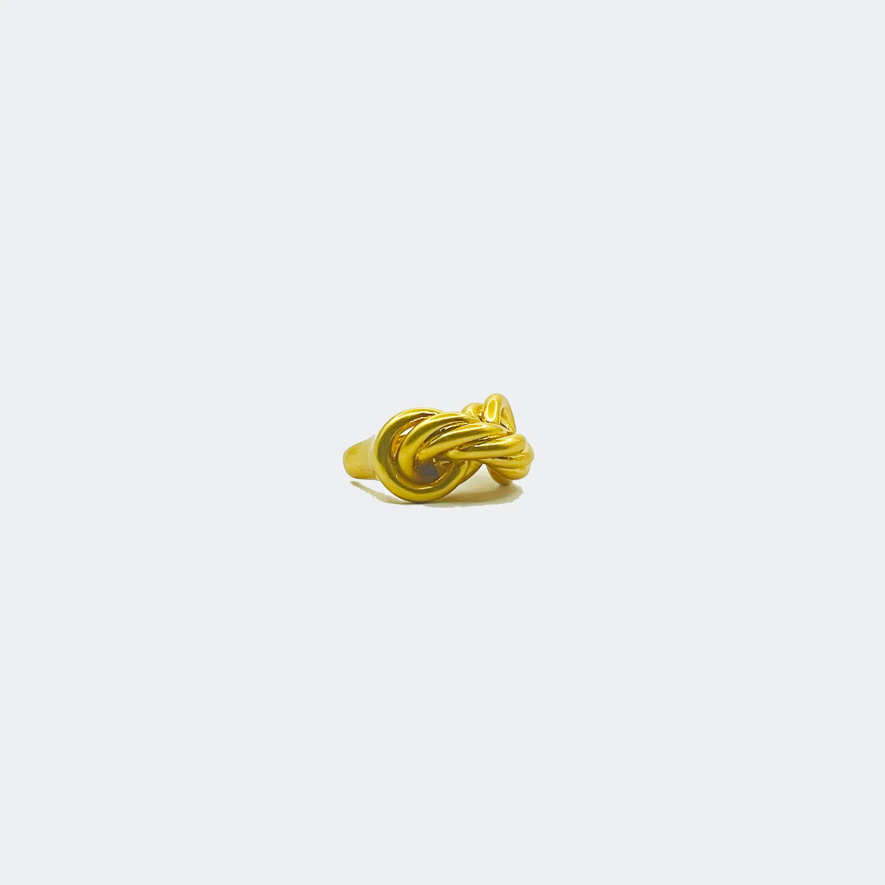 Gold knot ring with twisted design on plain white background