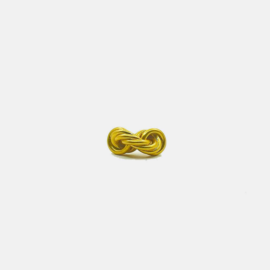 Gold knot cufflink on white background, minimalist jewelry accessory