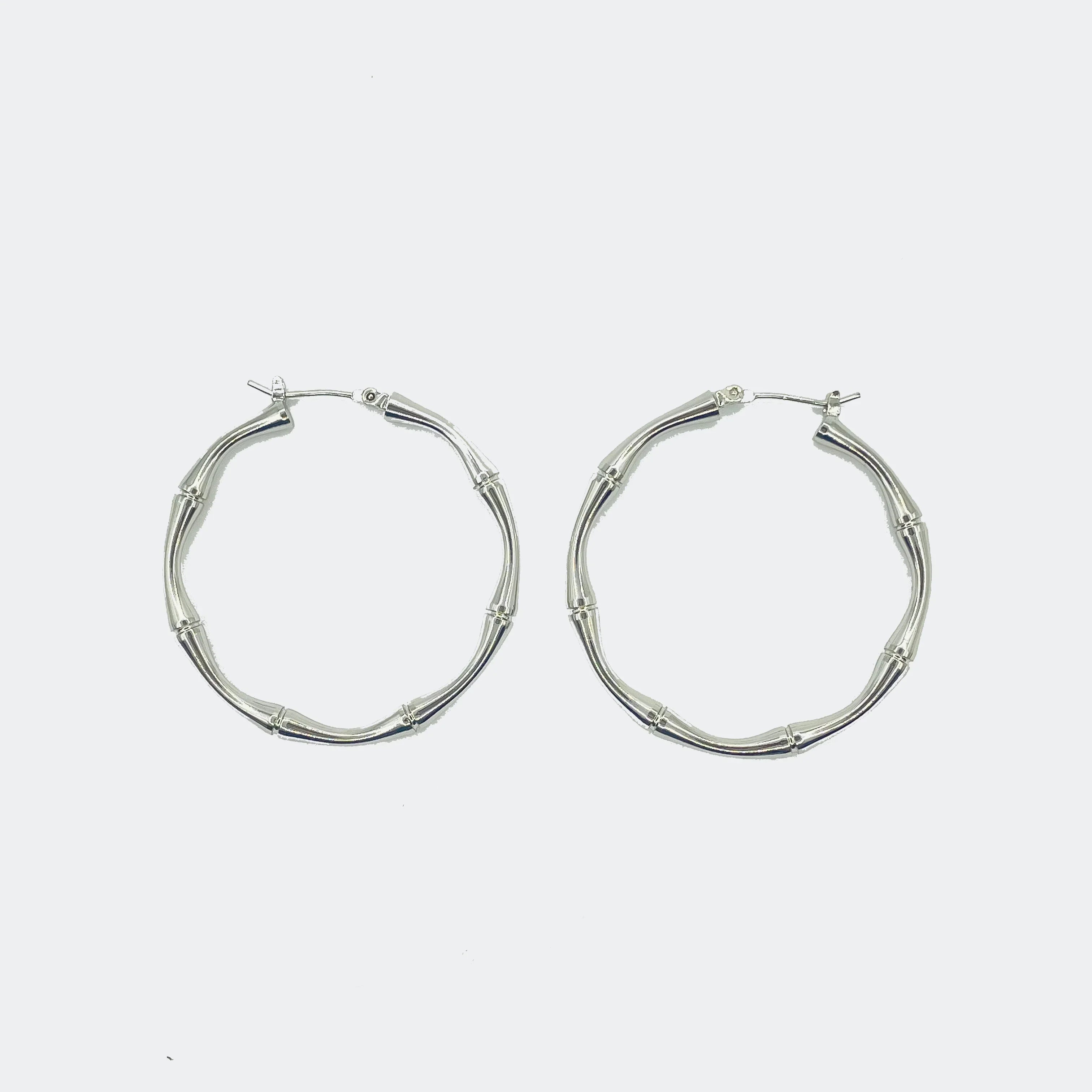 Silver bamboo-style hoop earrings on a white background